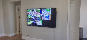 Wall-mounted TV displaying multiple surveillance camera feeds, emphasizing security monitoring solutions for businesses in a modern interior setting.