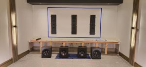 Audio equipment setup with four speakers on a wooden table against a wall, showcasing a sound system installation for enhanced IT services and digital solutions.